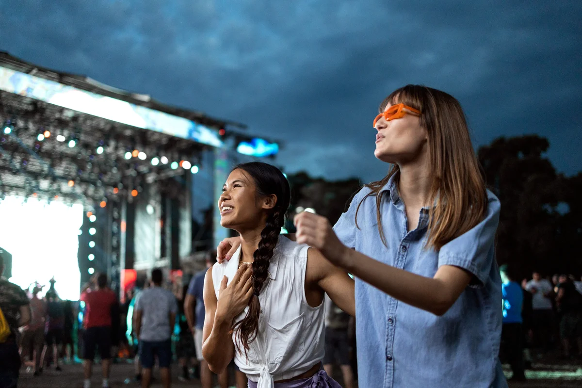 girls dance in front of a stage at a festival