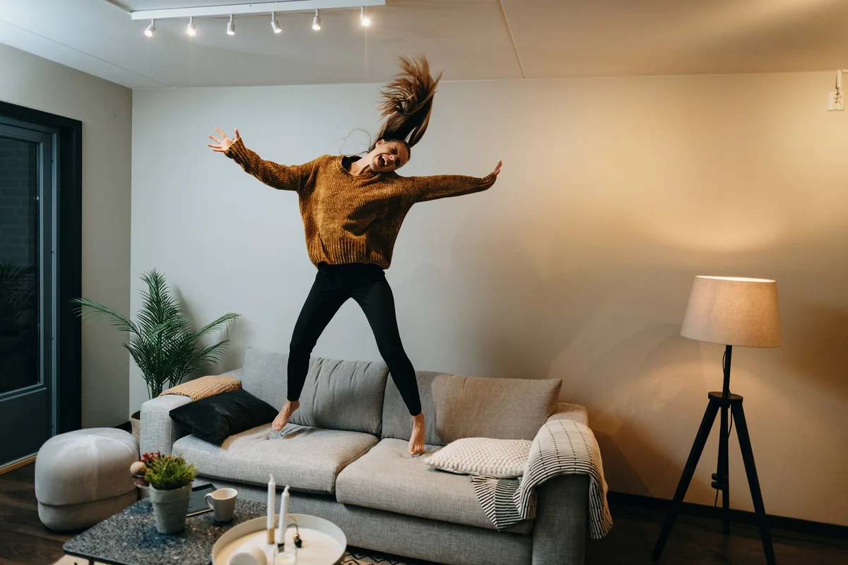 Woman dancing and jumping on sofa