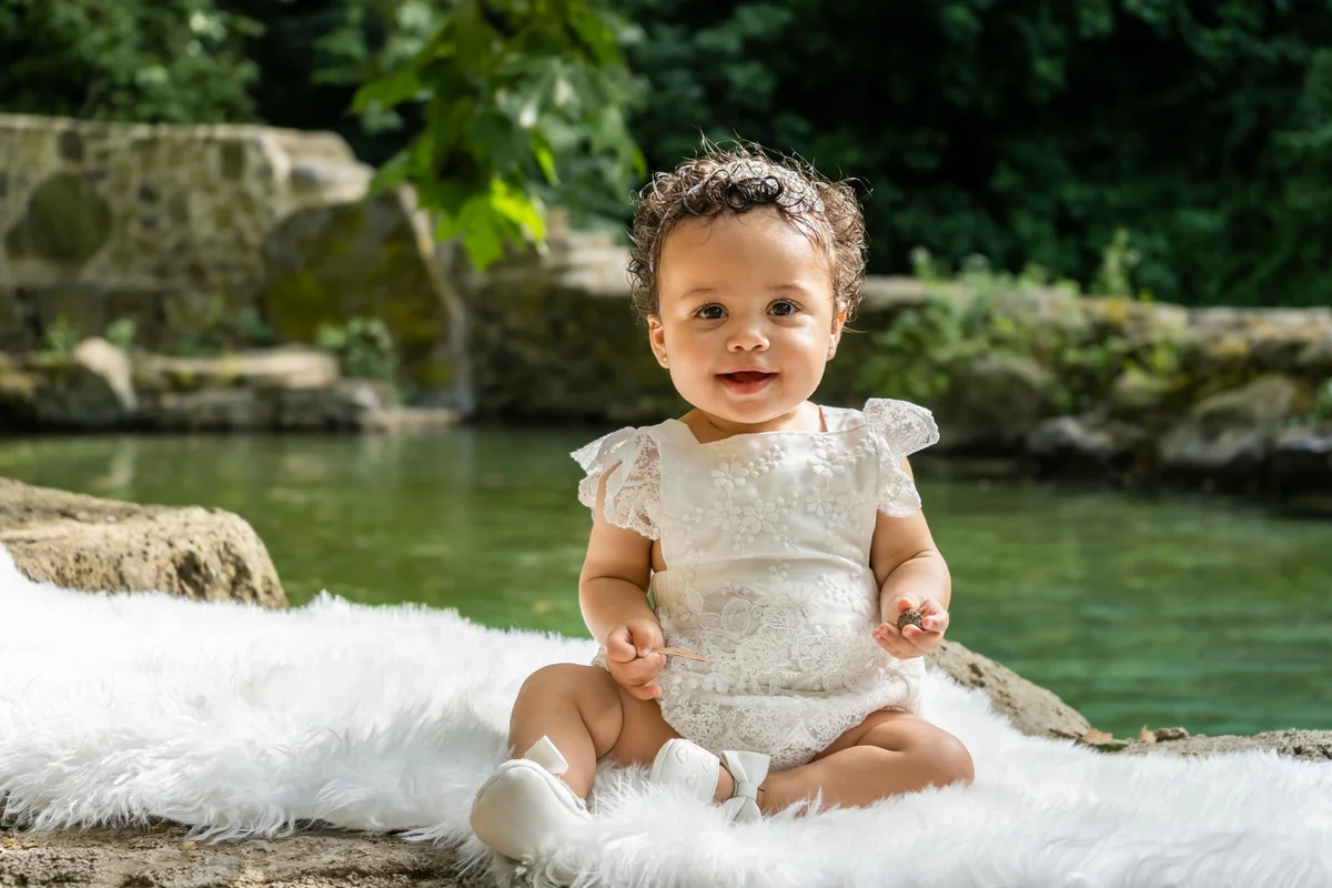 Adorable baby girl having fun playing in nature river park