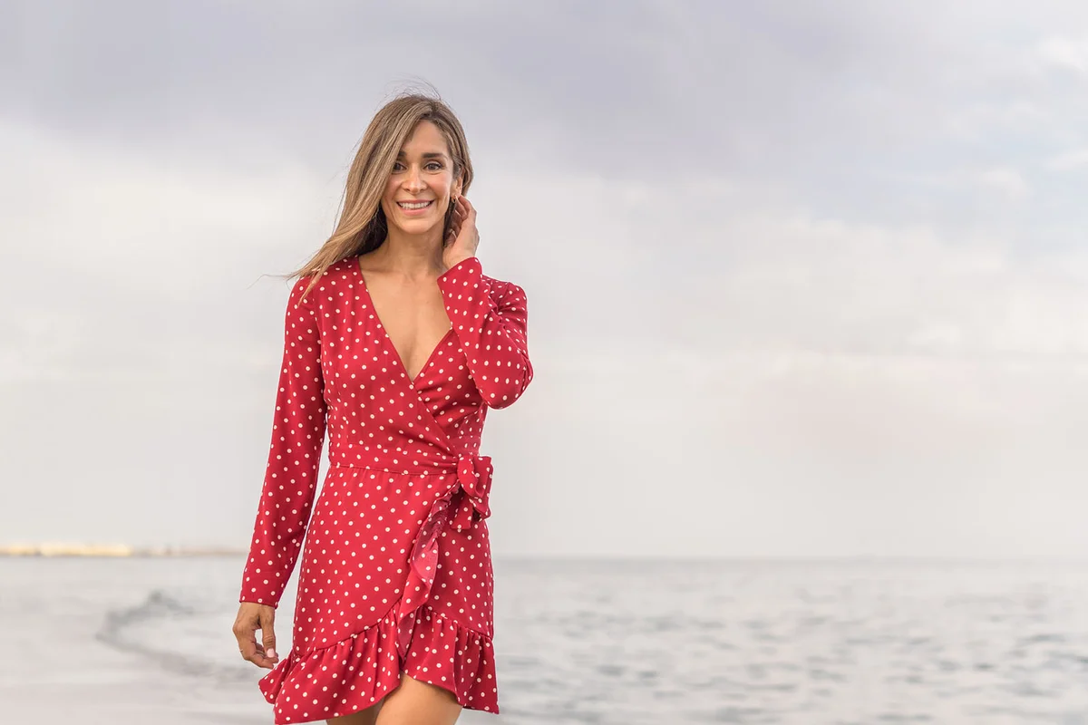 Woman in red dress enjoying summer holidays relaxing on beach at sunset