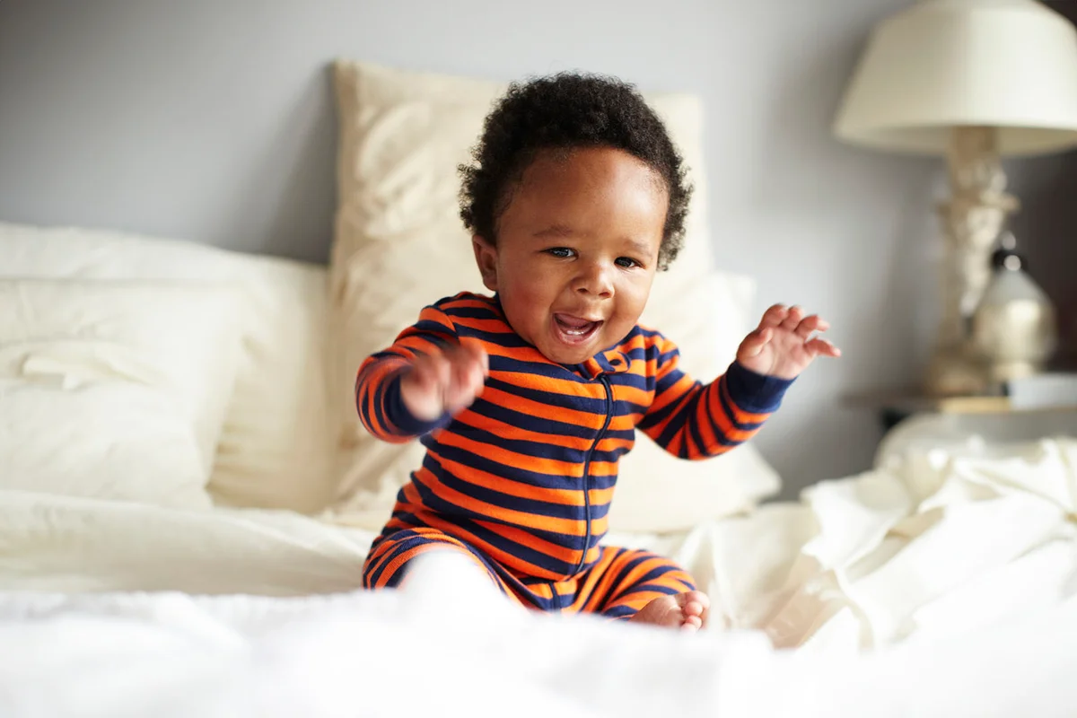 Baby boy sitting on bed