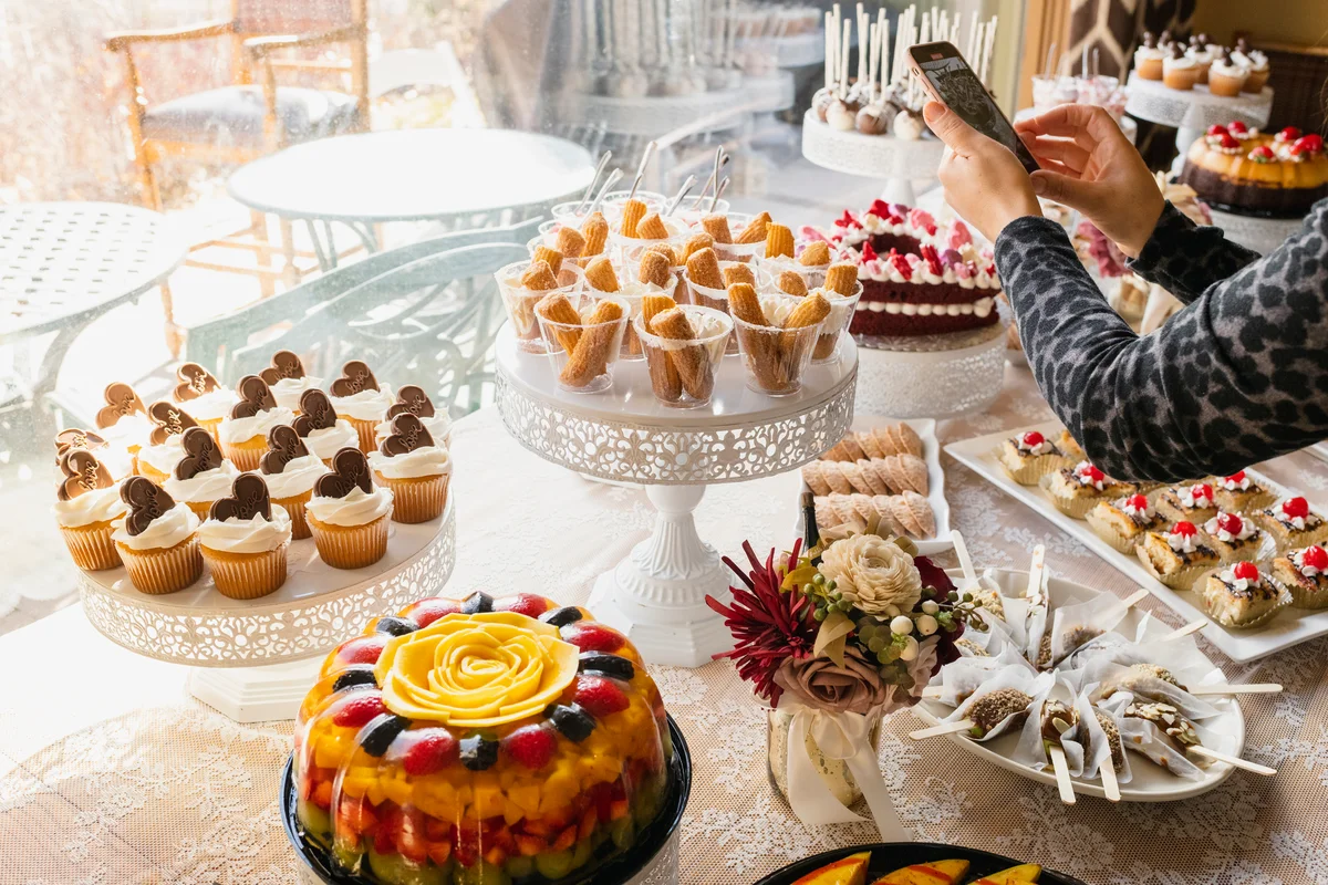 Woman photographing pastries on buffet table