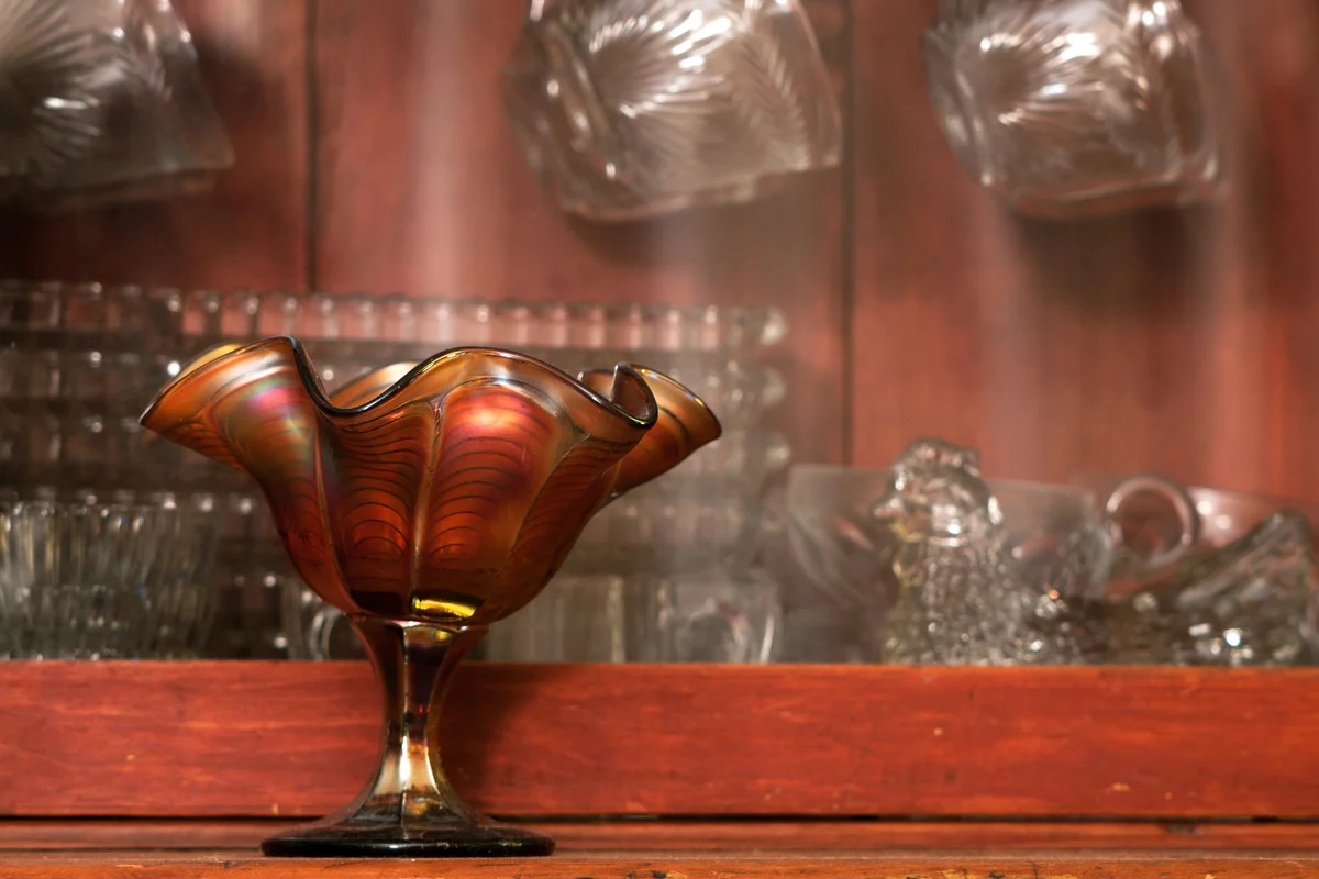 Various antique glassware pieces displayed in an antique hutch