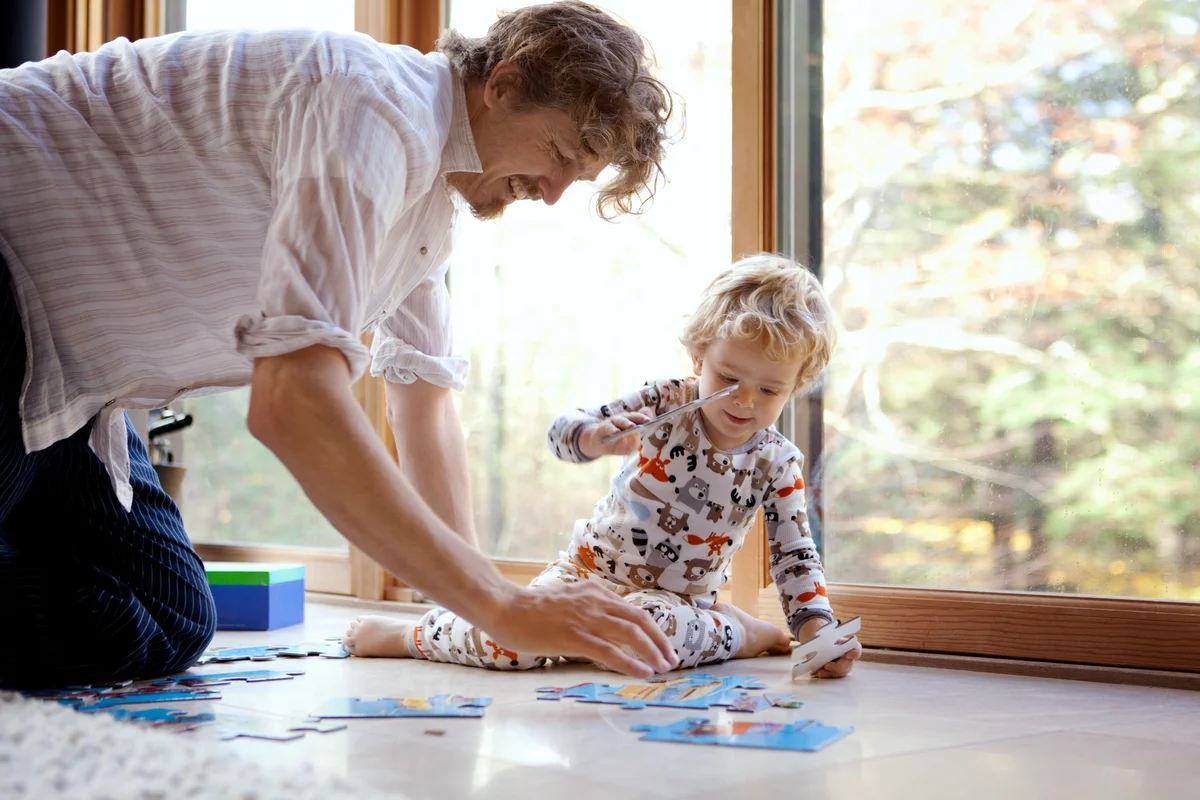 Father and son arranging jigsaw puzzle at home