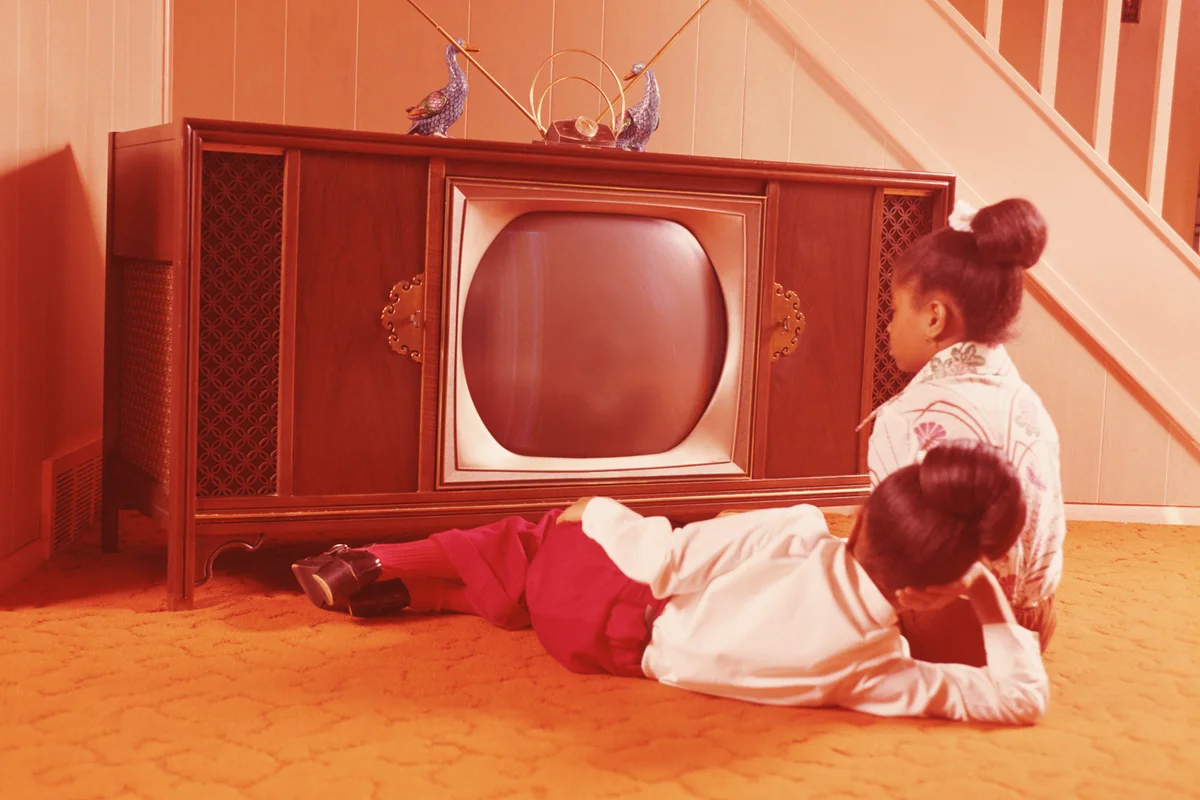Two girls on living room floor, watching television