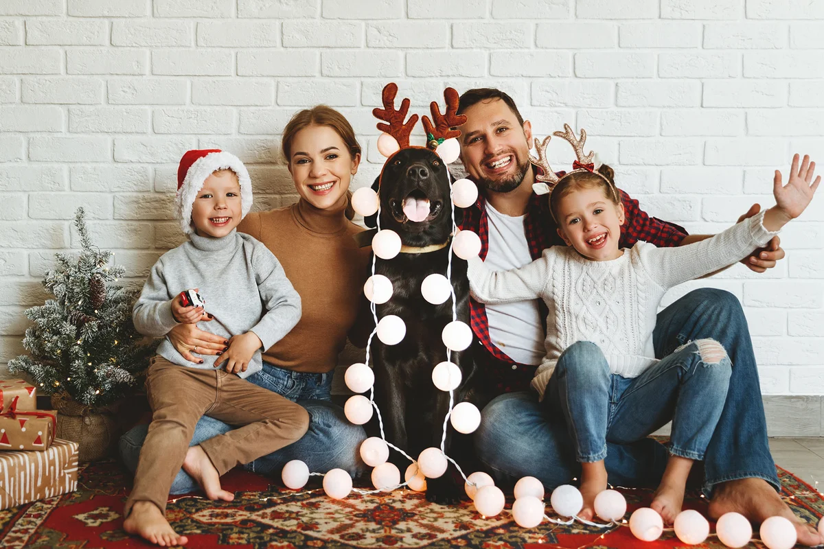 family mother father and kids with dog before Christmas with garland and tree