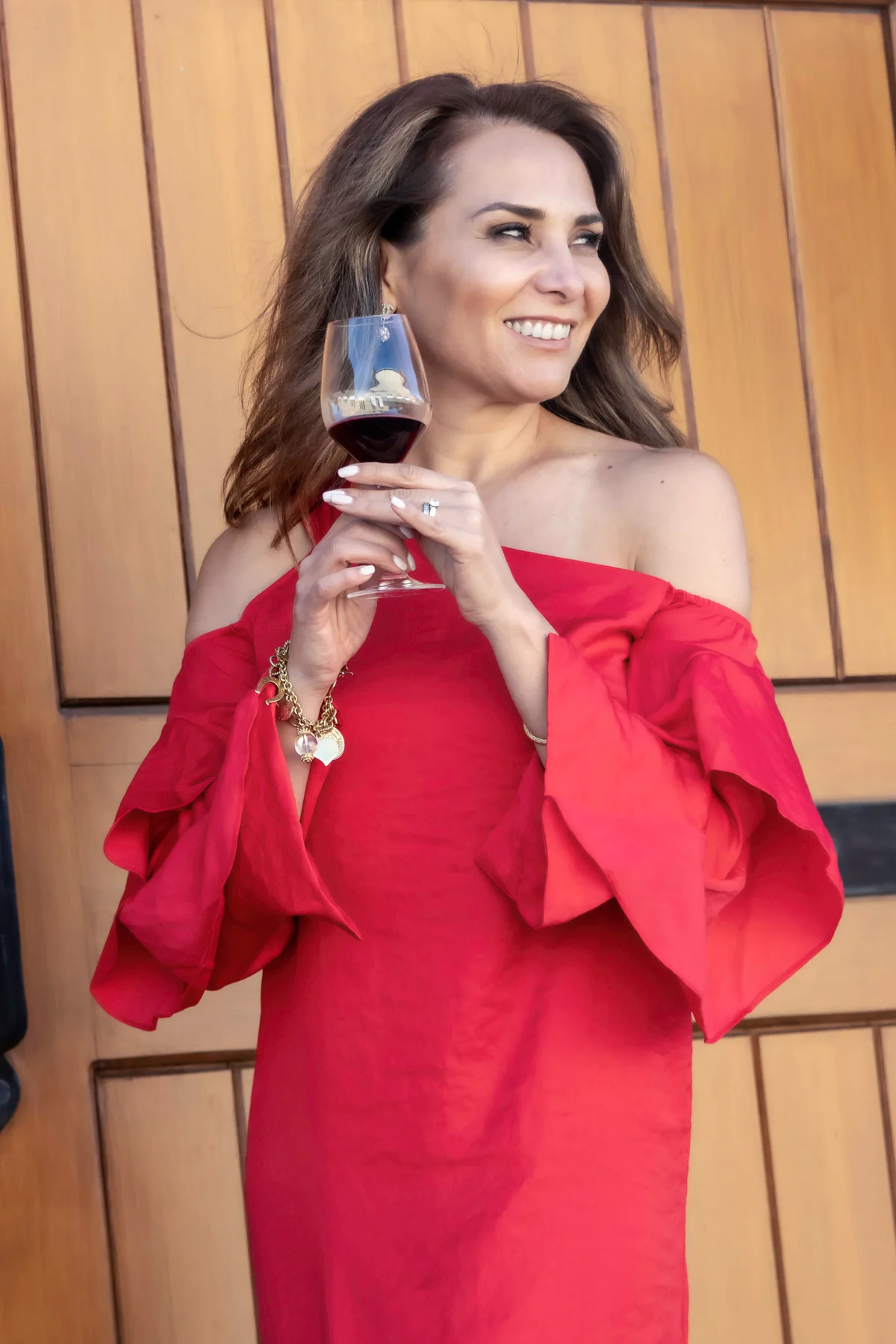 Smiling woman in a red dress having a glass of wine
