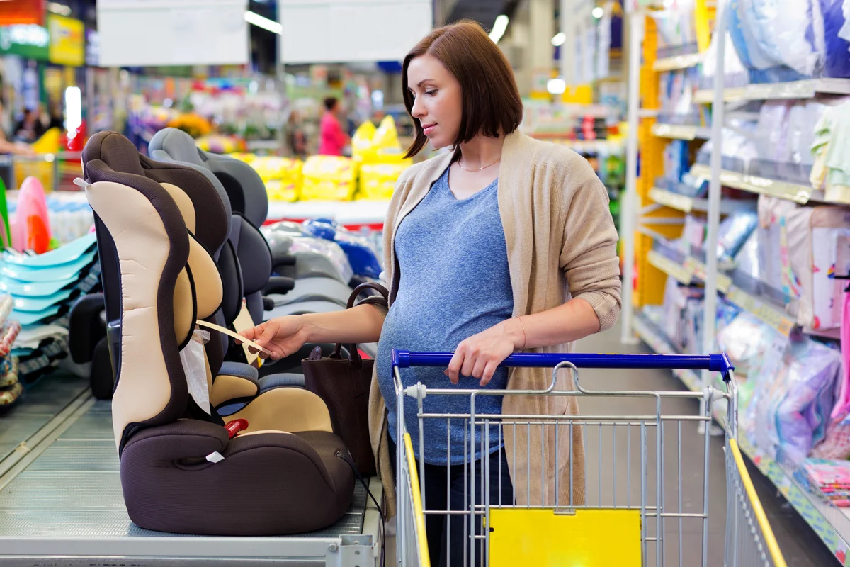 Pregnant woman in shop buy car baby seat