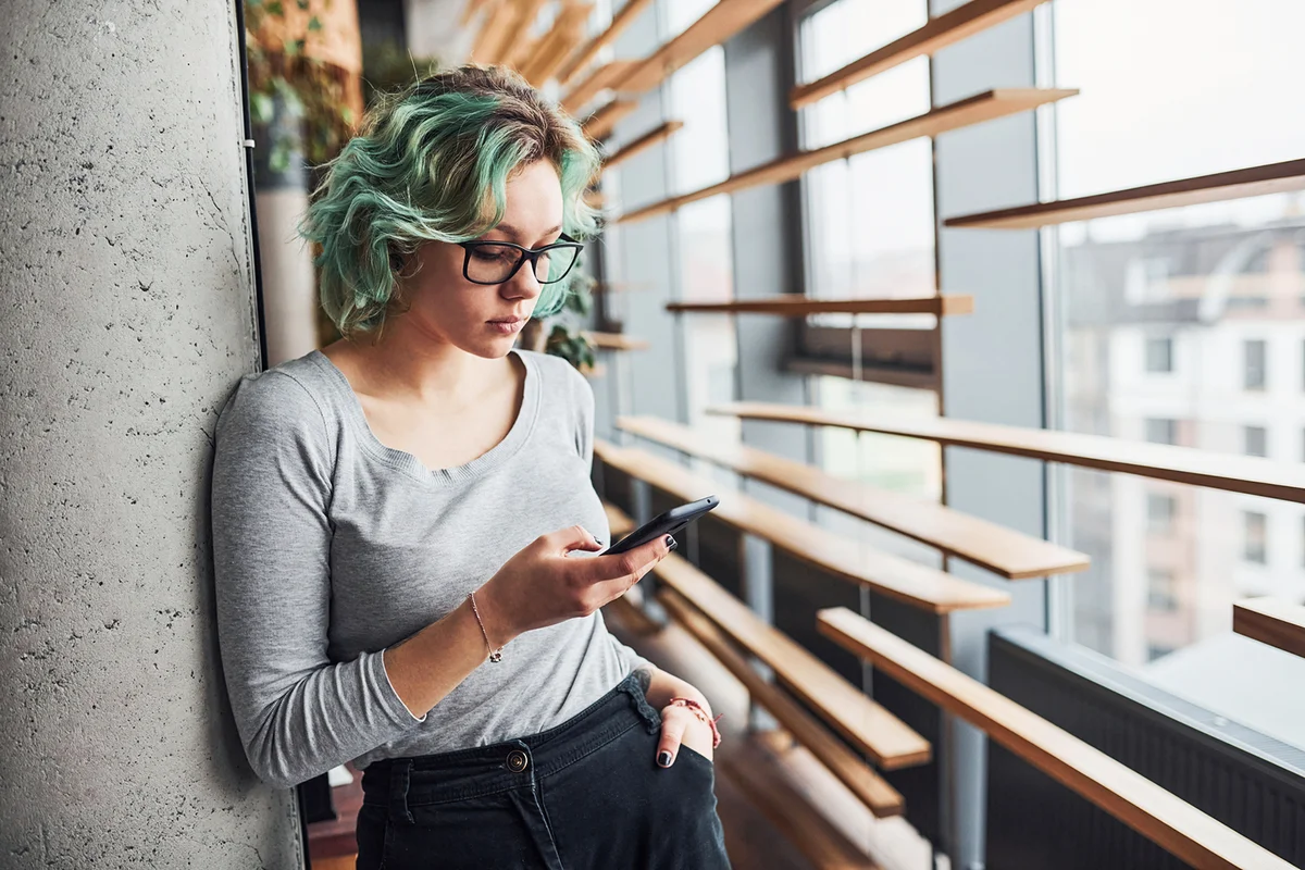 Girl with green hair standing indoors