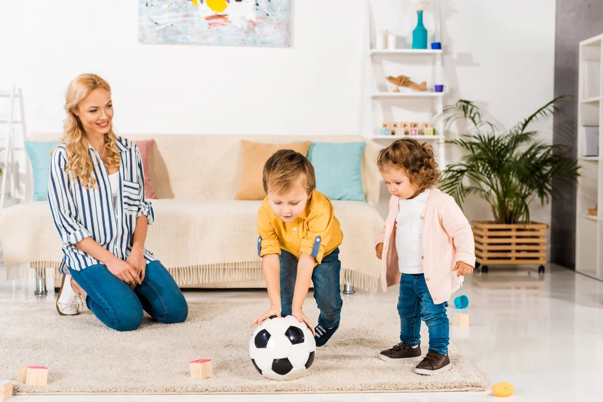 Mother looking at children playing soccer at home
