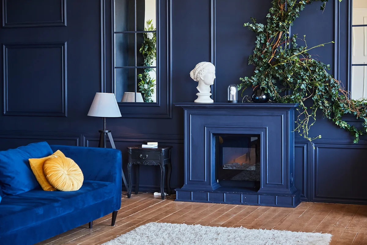 Modern interior with fireplace, spacious living room with dark blue walls and wooden floor.