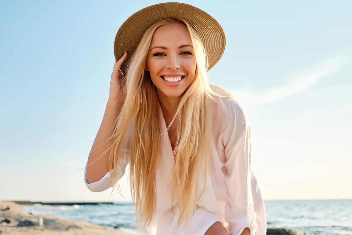 Smiling blond woman in white shirt at the beach