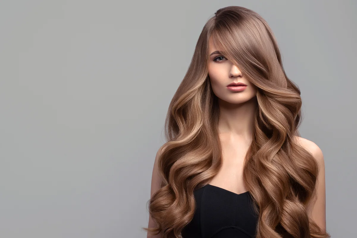 Woman with long wavy hair and side-swept bangs
