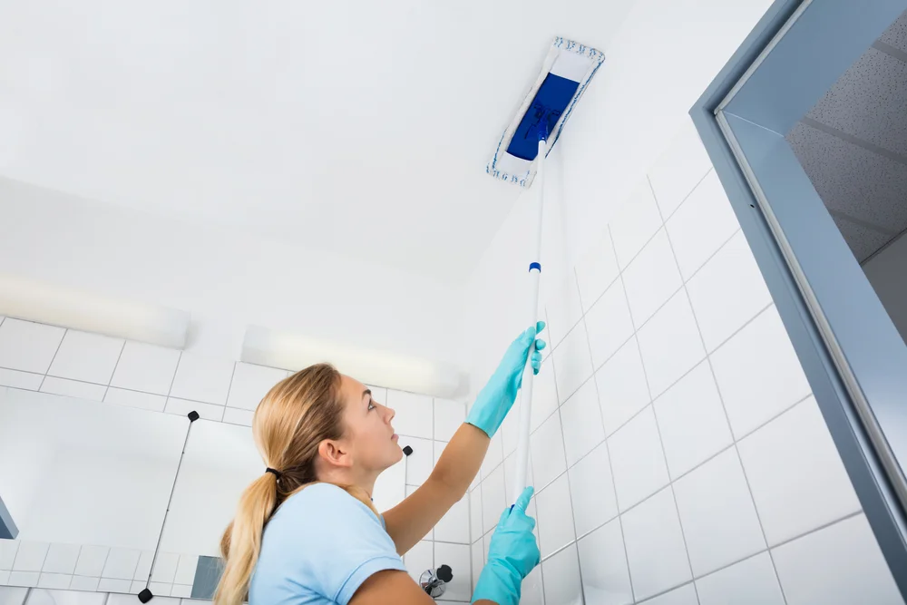 woman cleaning a bathroom ceiling