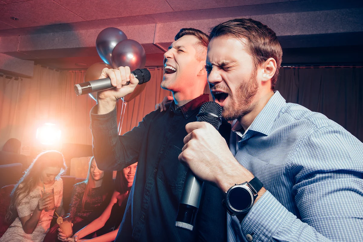 Men singing in microphone in karaoke bar