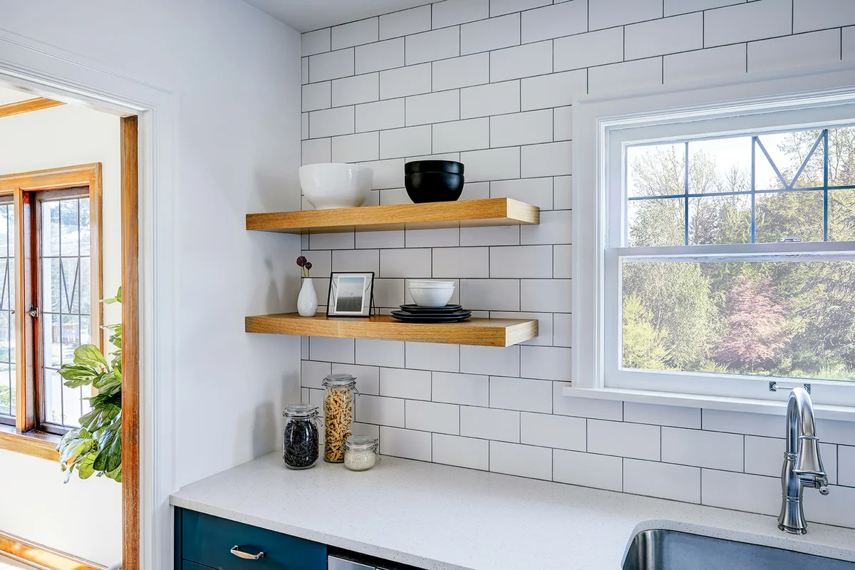 Kitchen with floating shelves and white tile backsplash