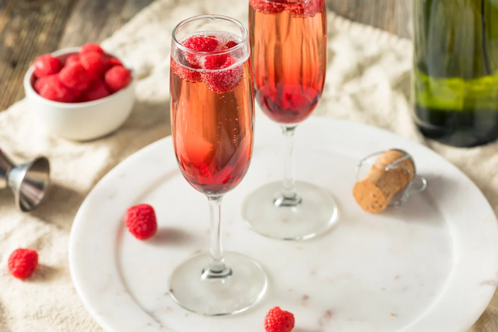 Two filled Champagne flutes in a plate and a table background