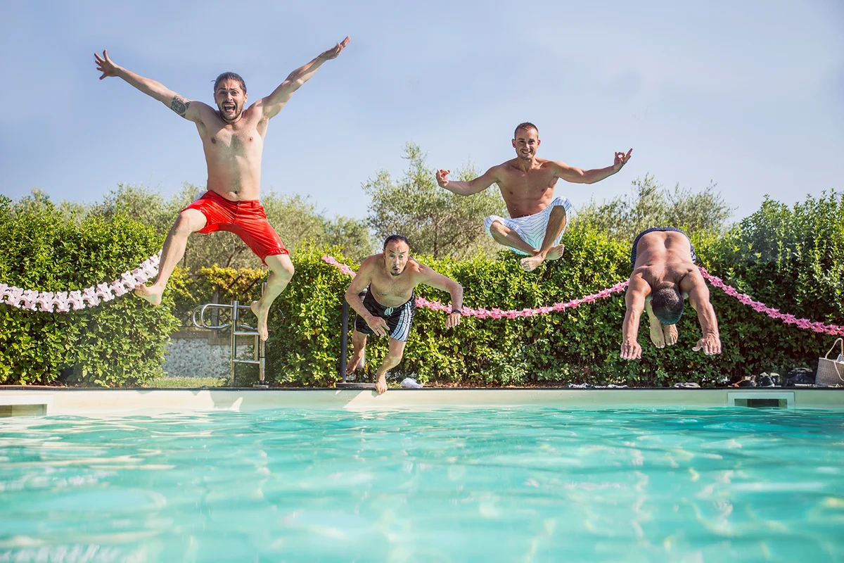 Friends jumping into a swimming pool