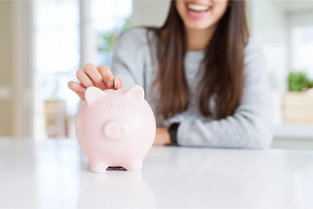 Woman at home saving money in a piggy bank