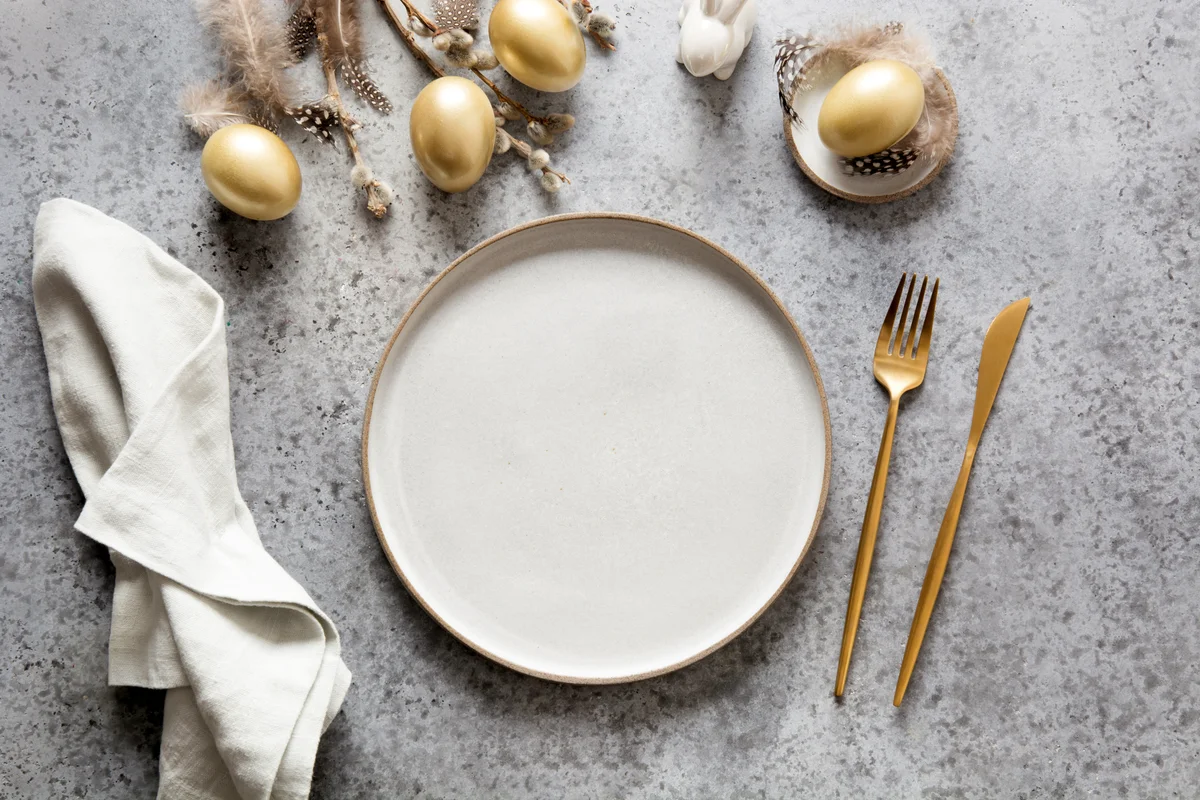 Elegant Easter table setting with golden eggs on grey stone table