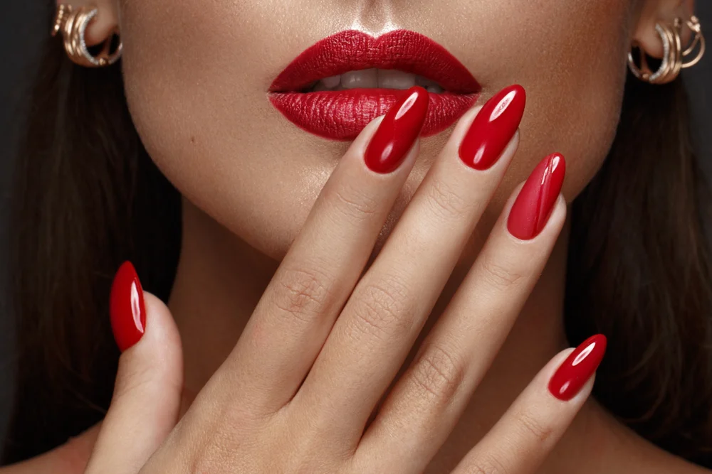 Close up of a woman's face with red lips and nails
