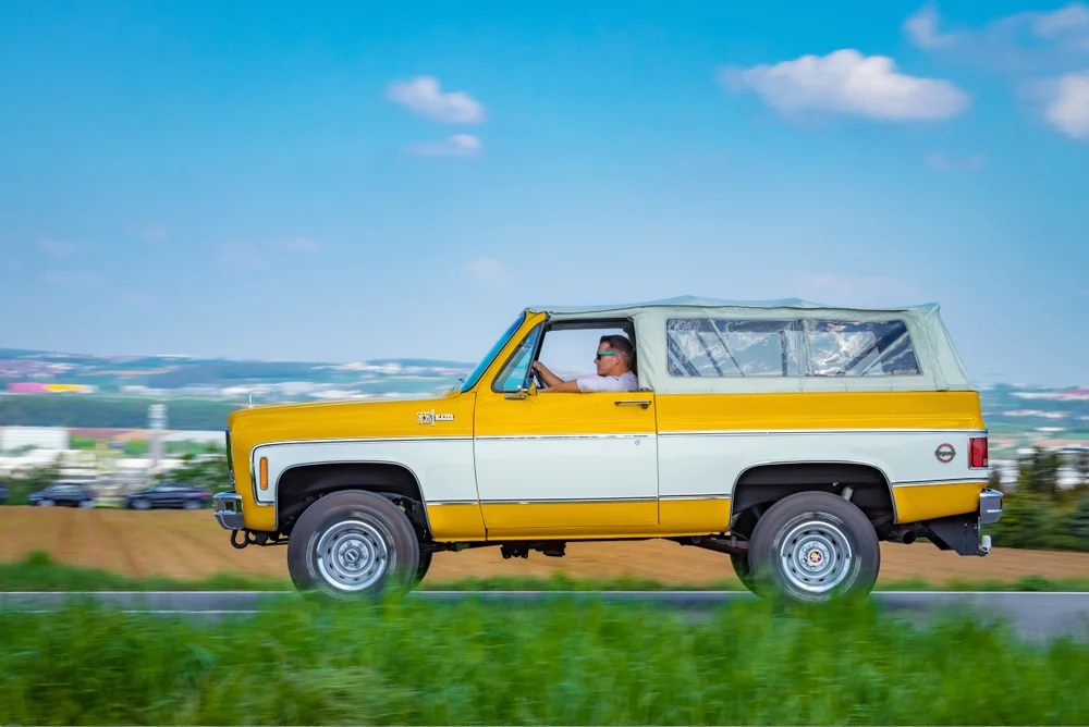 Man driving a yellow and white Chevrolet K5 Blazer