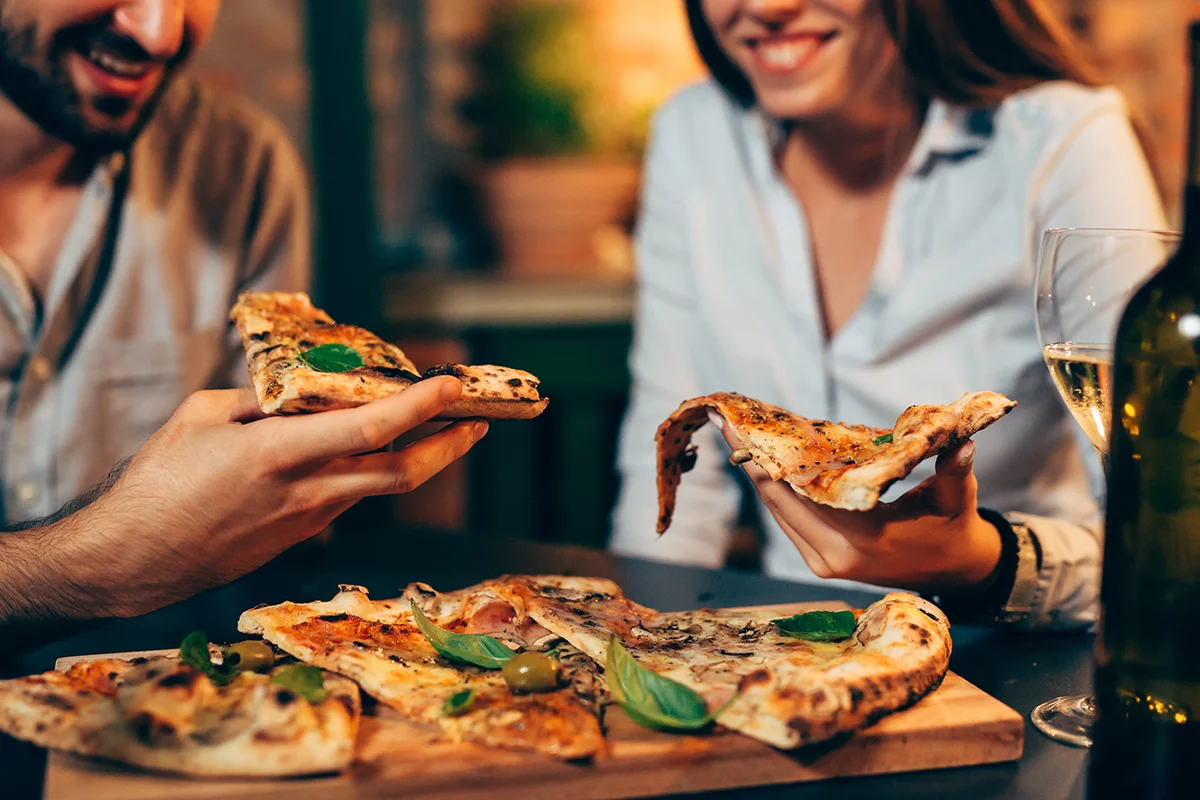 close up of people eating pizza