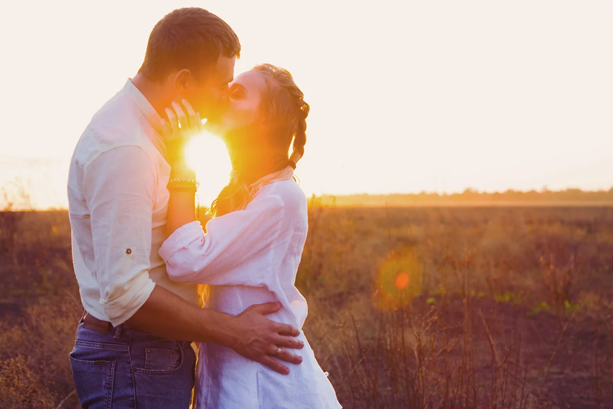 Couple kissing against sunset