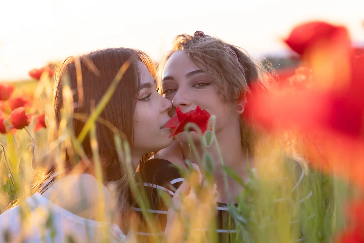 Lesbian couple kissing in a poppy field