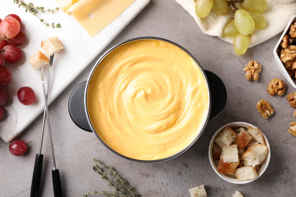 Top view of fondue in a table with grapes, walnuts and tools