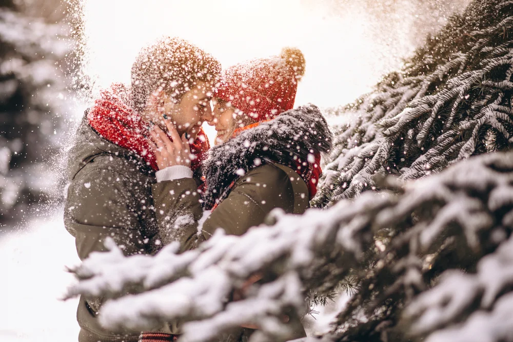 Young couple looking at each other between trees and snow