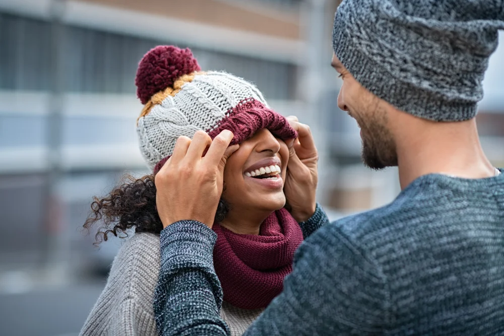 Goofy couple laughing together with winter hats