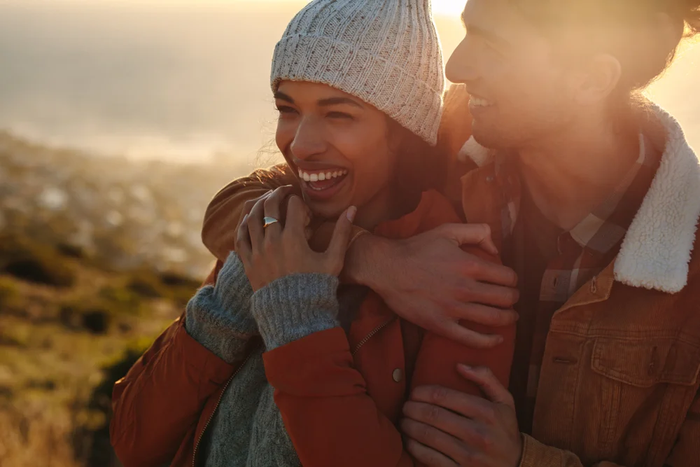 Close up portrait of young man hugging his partner and smiling on a winter day