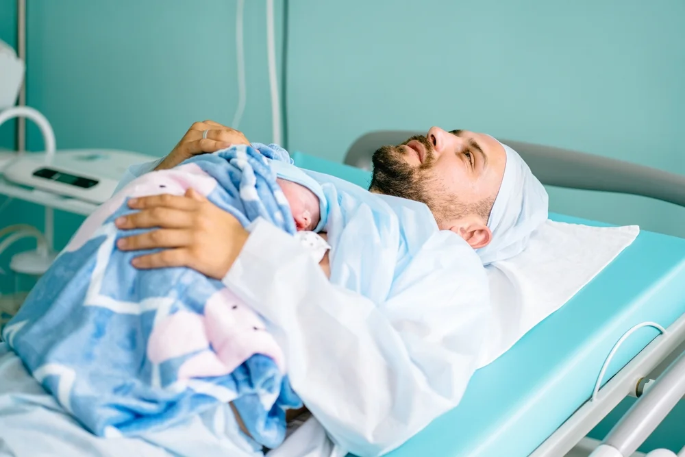 Man lying down with his baby in the delivery room