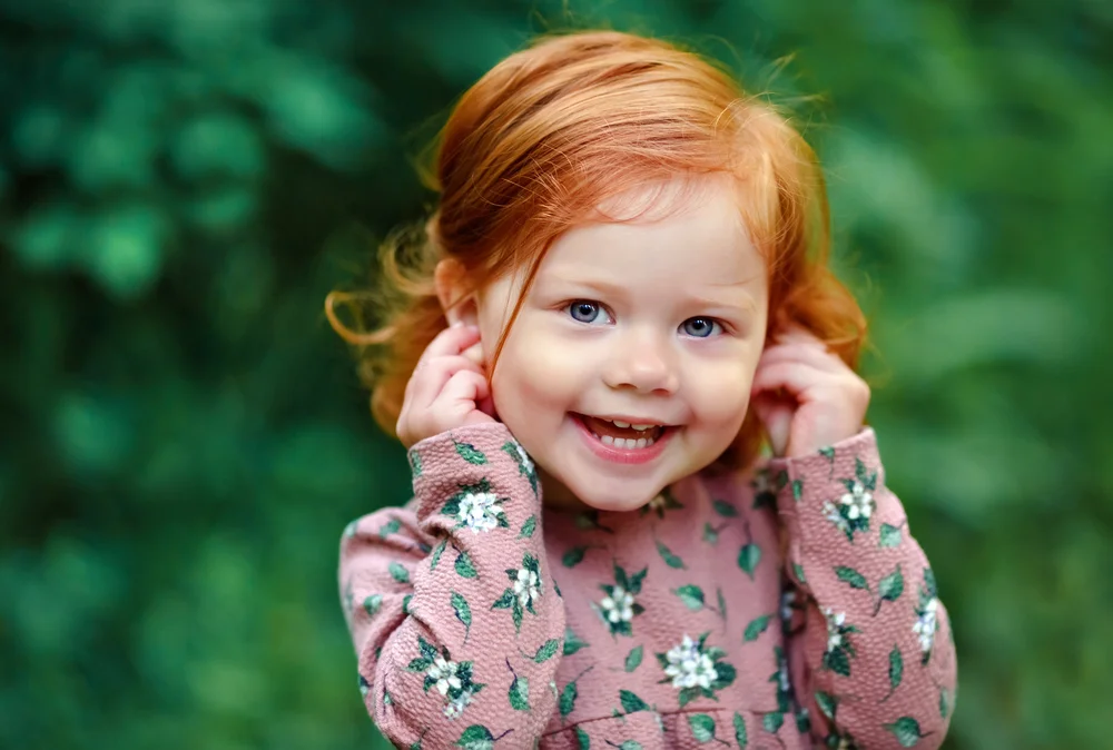 Cute red-haired girl with a green nature background