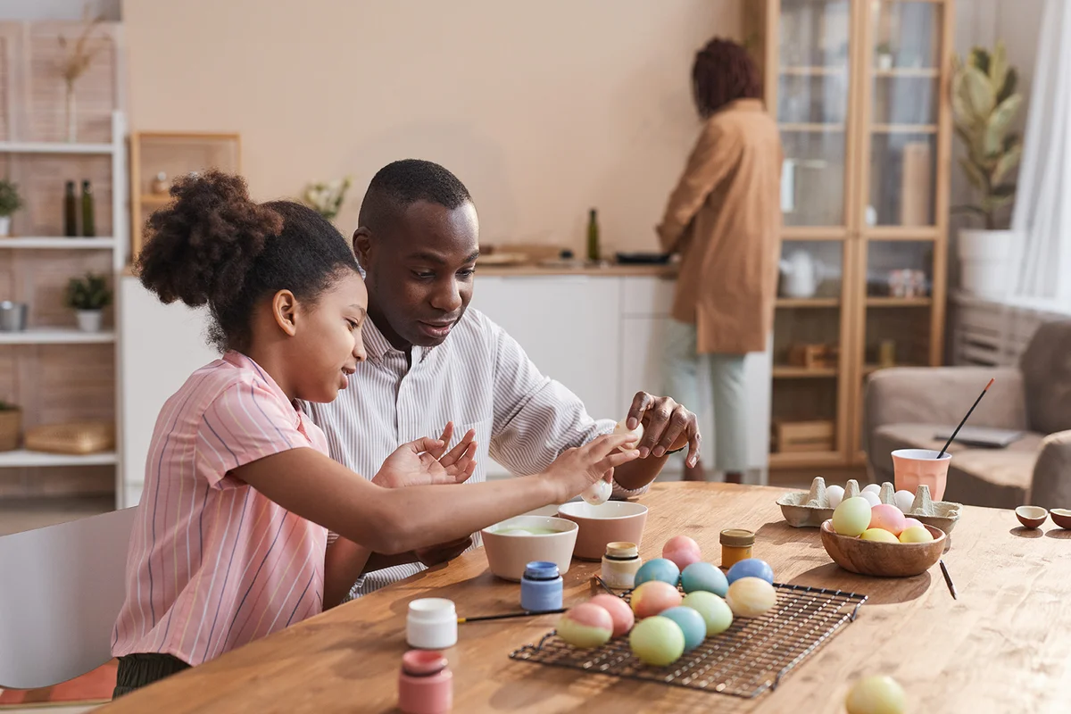 girl painting Easter eggs with father