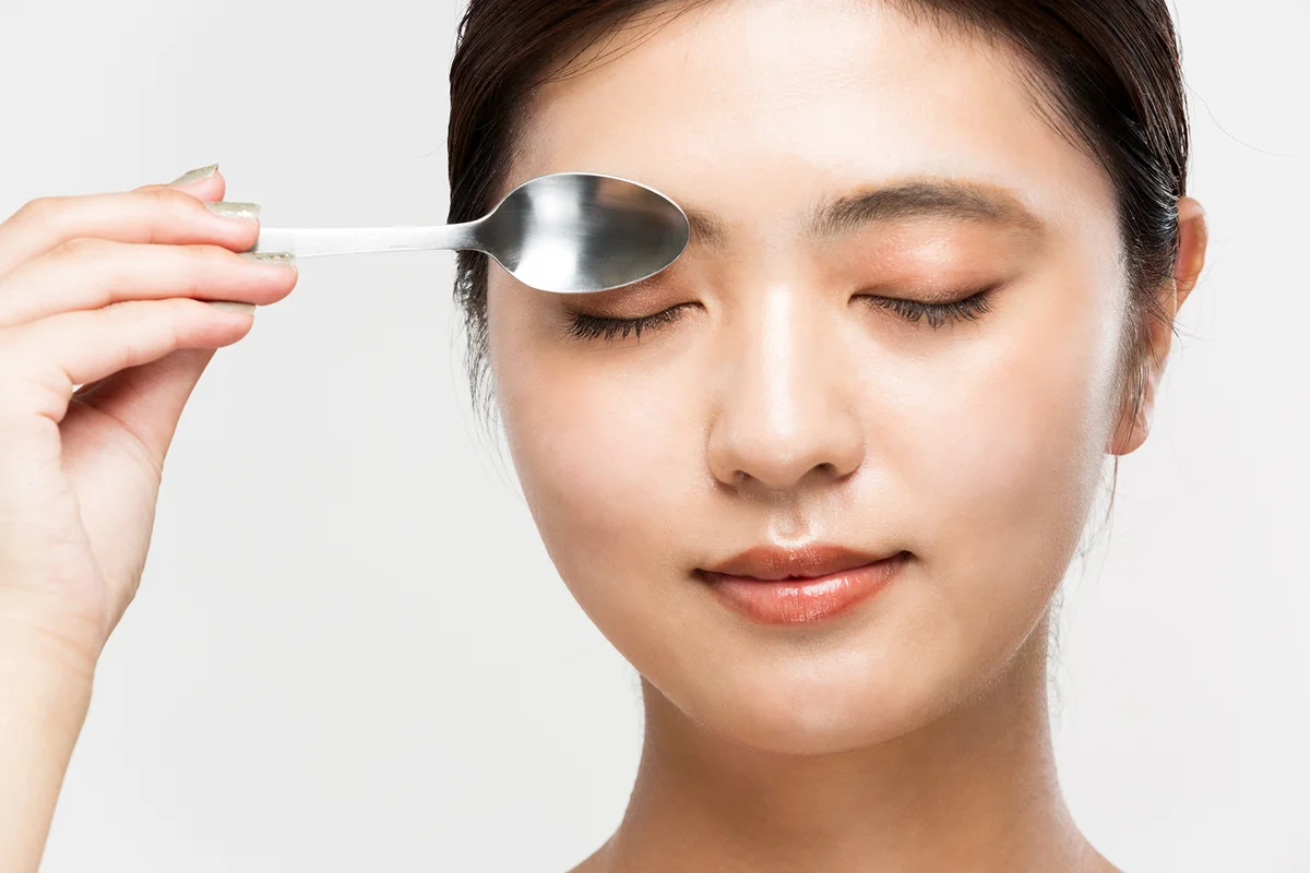 Woman with spoons on eyes