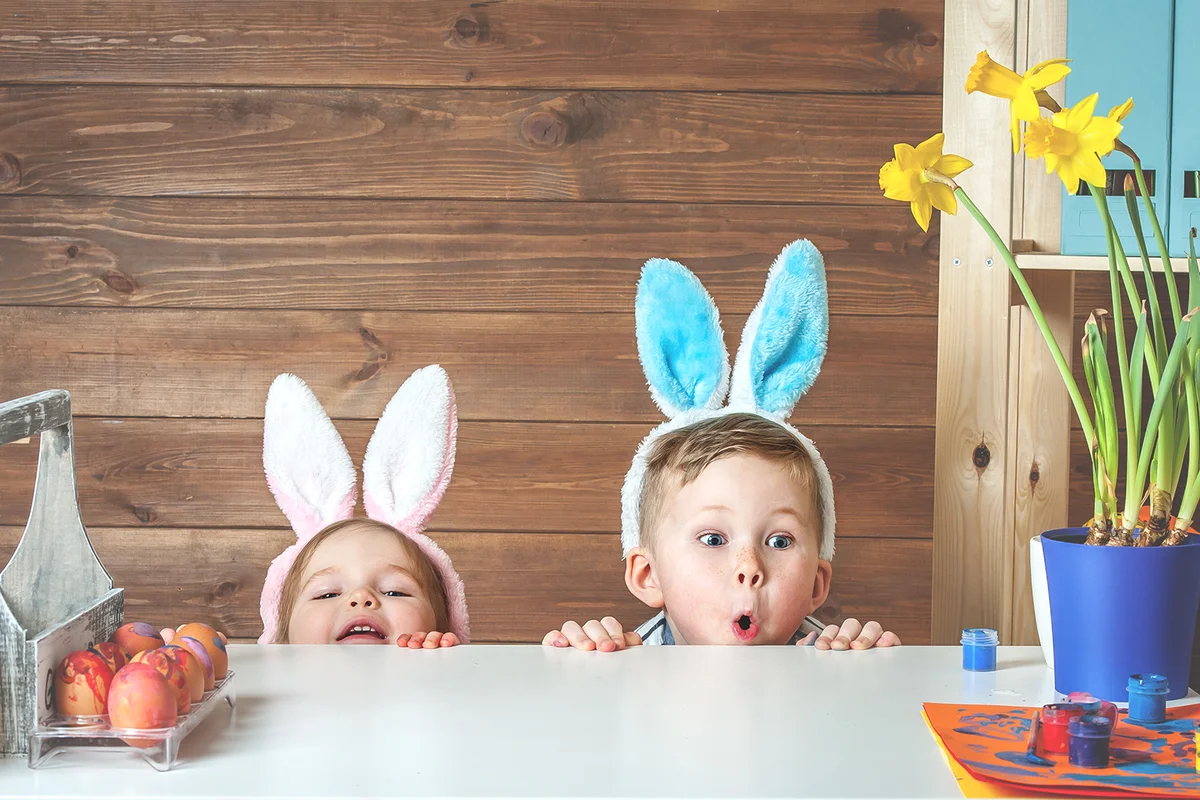 Child boy and girl wearing bunny ears and painting eggs