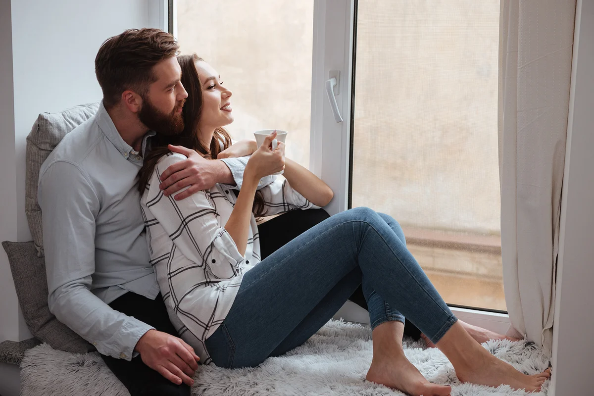 Loving couple sitting together and look at window
