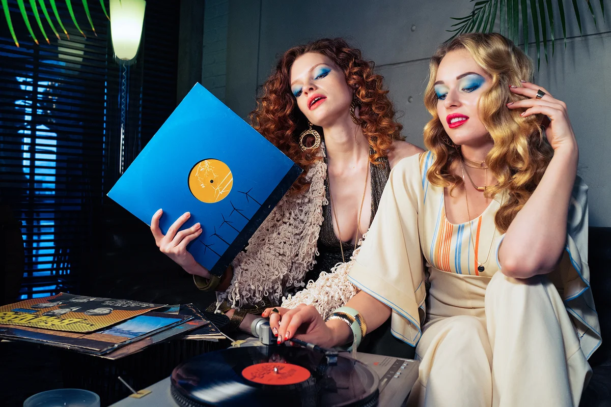 Two pretty girls models listening to vinyl records on the oldschool turntable