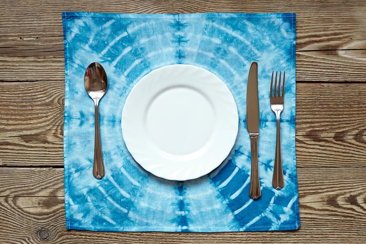 Empty plate on wooden tabletop with tablecloth close up