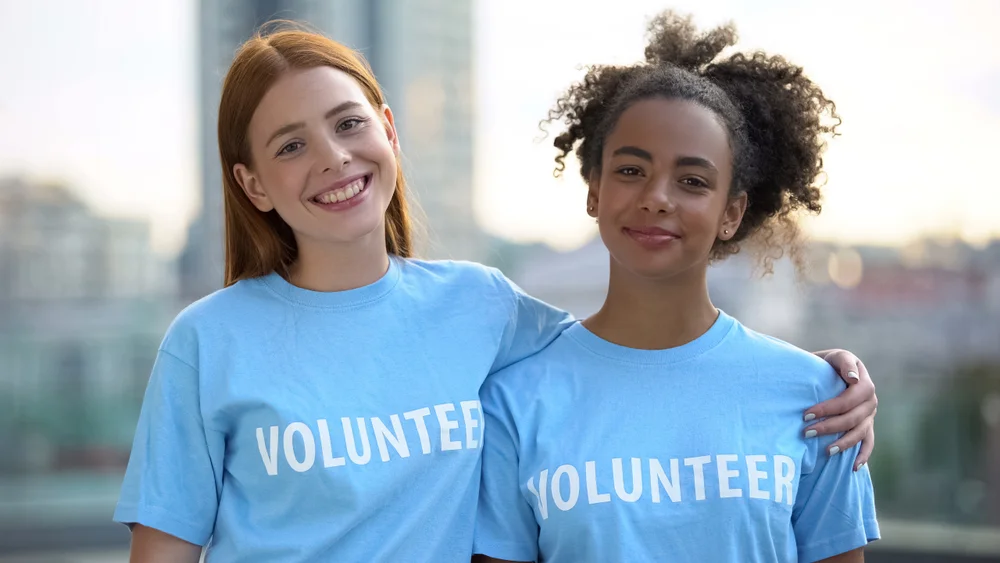 Two female teen volunteers smiling on camera