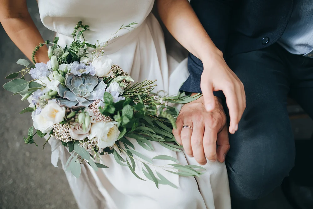 Detail of bouquet with bride and groom's hands