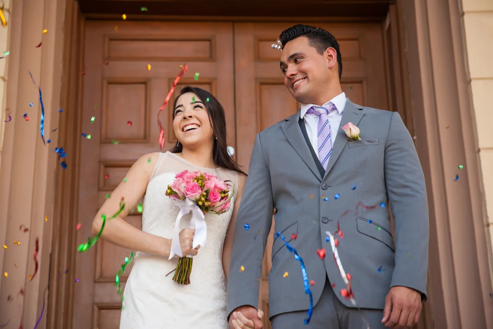 Happy bride and groom outside courthouse with confetti