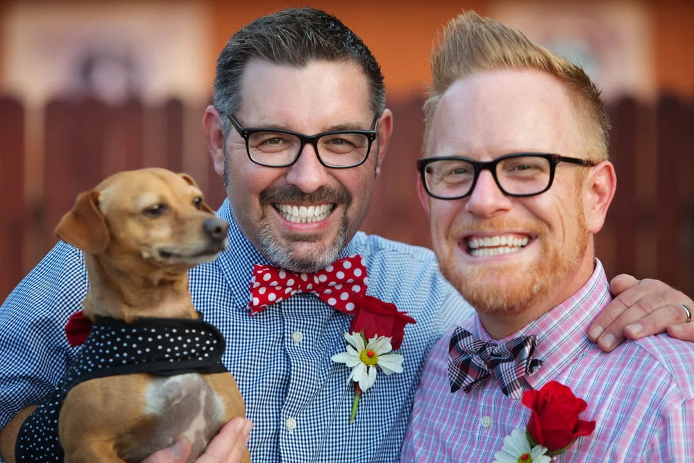 Gay couple holding their dog at their wedding