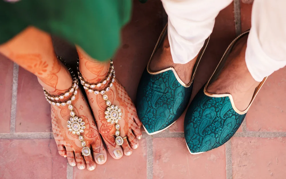 Detail shot of Indian bride and groom's shoes and beautiful henna tattoos