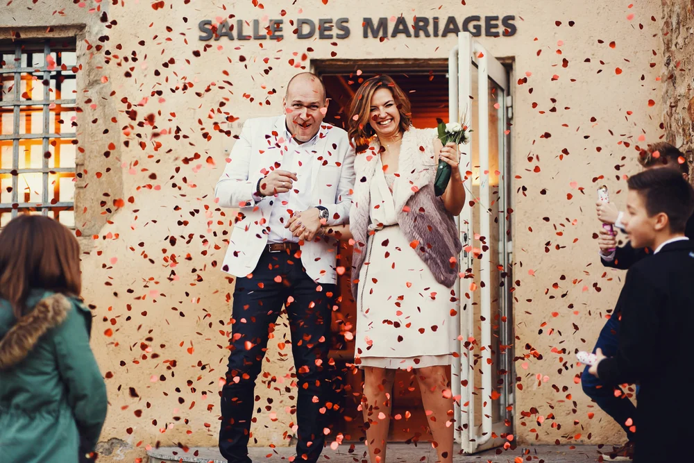 Newlywed happy couple leaving the courthouse among confetti