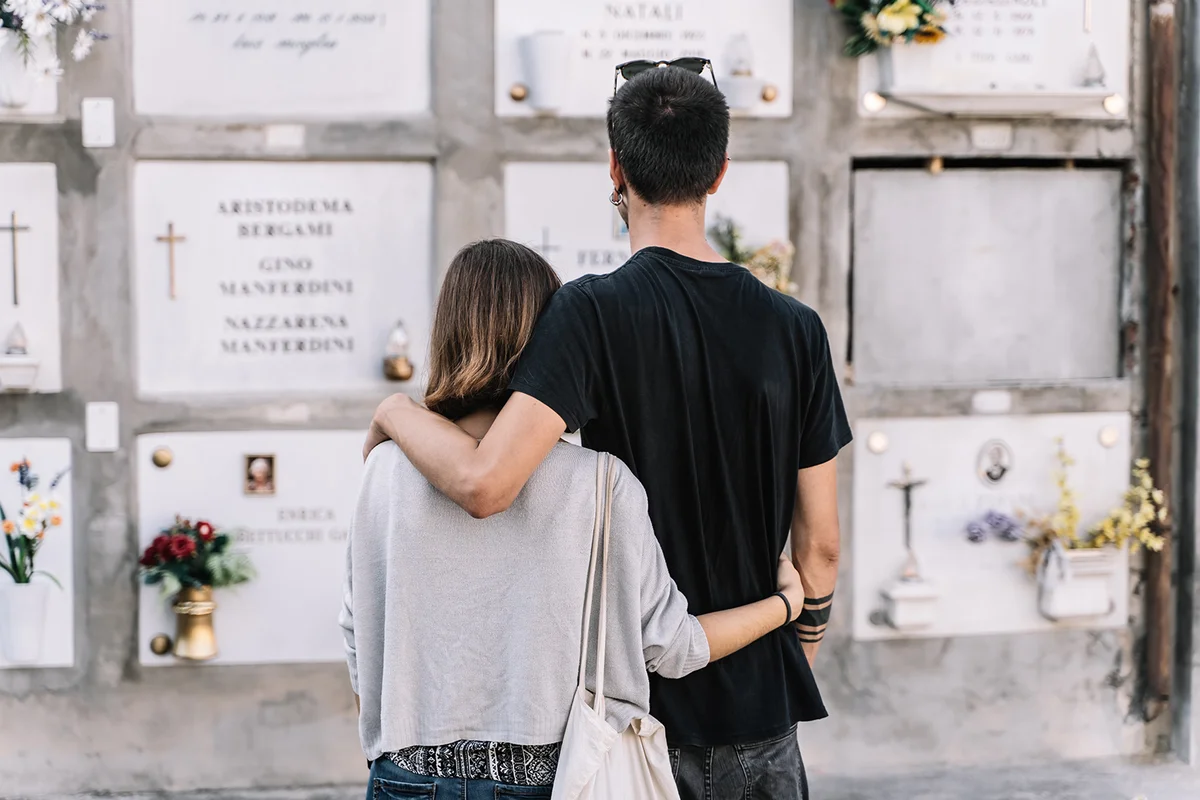 Couple on their backs hugged in front of a cemetery wall