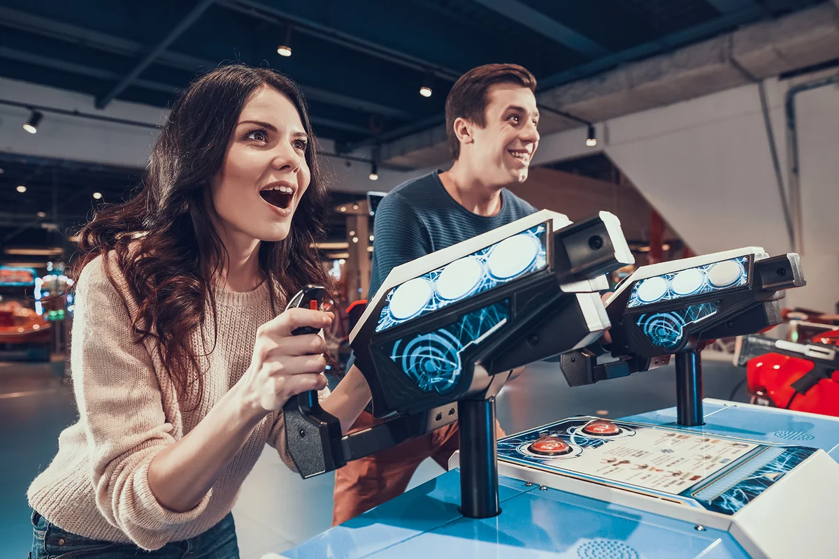 Man and woman are piloting blue spacecrafts playing in arcade.