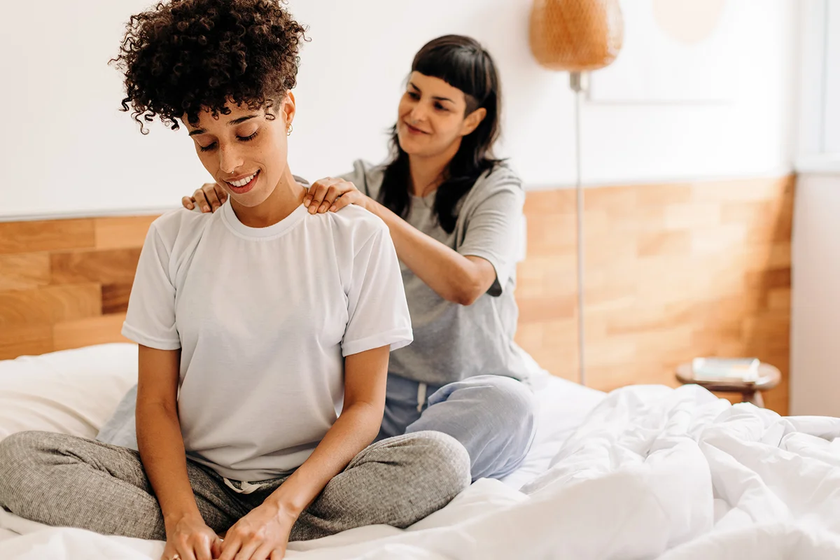 Caring young woman massaging her girlfriend at home